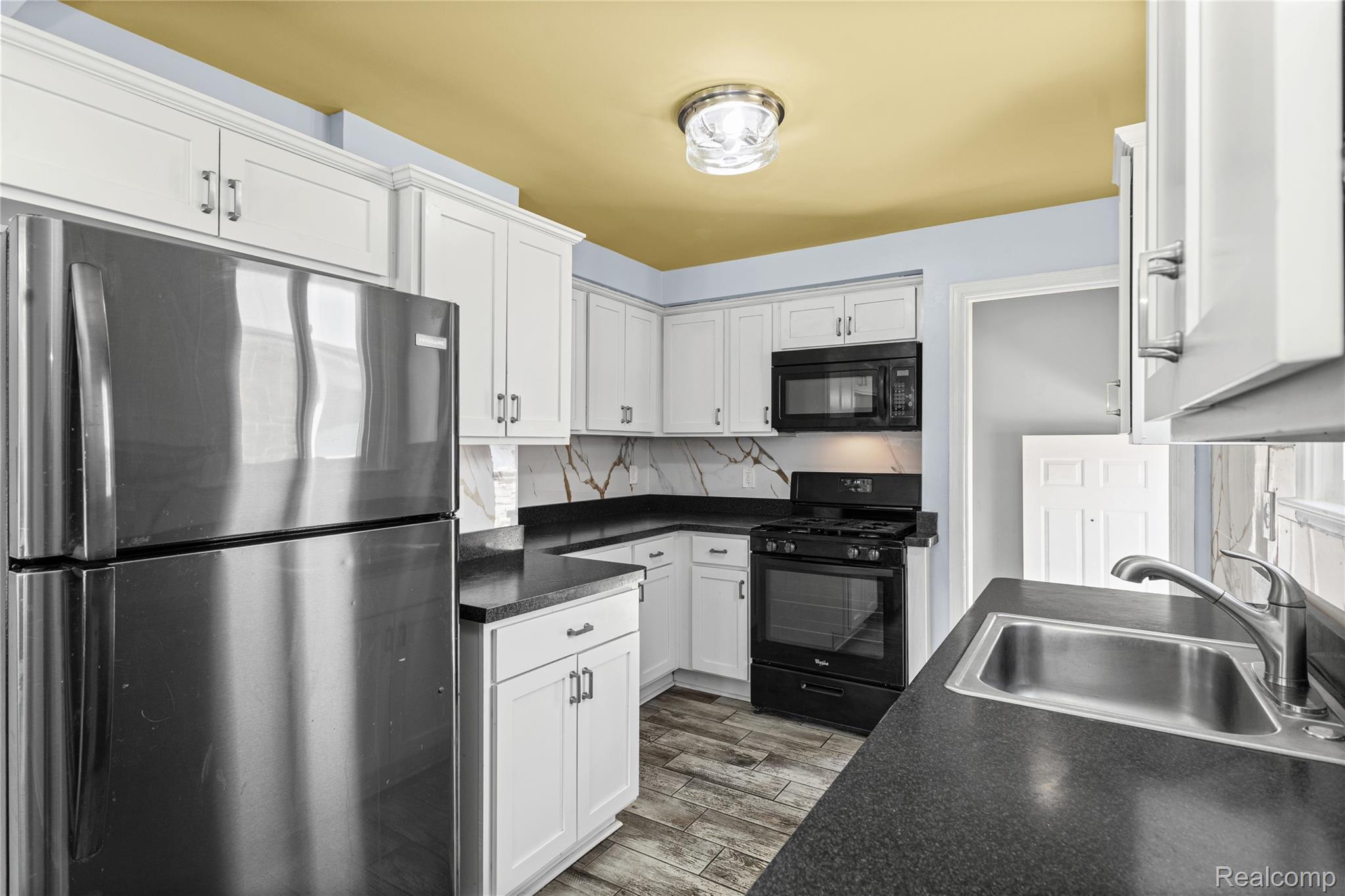 26508 Five Mile Road Redford, MI 48239 - Photo 15 of 41 Kitchen featuring white cabinetry, dark countertops, wood-finish flooring, a stainless steel refrigerator, and a black gas range with an overhead microwave