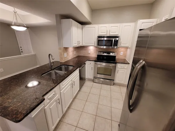 a kitchen with granite countertop a sink stove and microwave