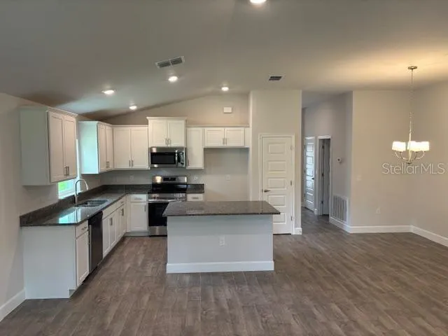 a kitchen with granite countertop a sink stove and refrigerator