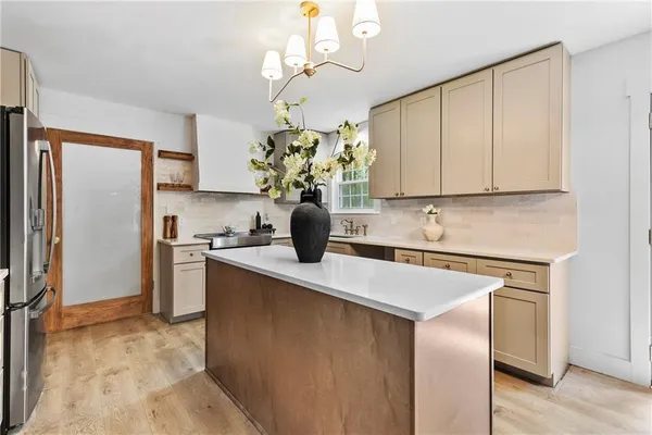 a kitchen with stainless steel appliances granite countertop a sink a refrigerator cabinets and wooden floor