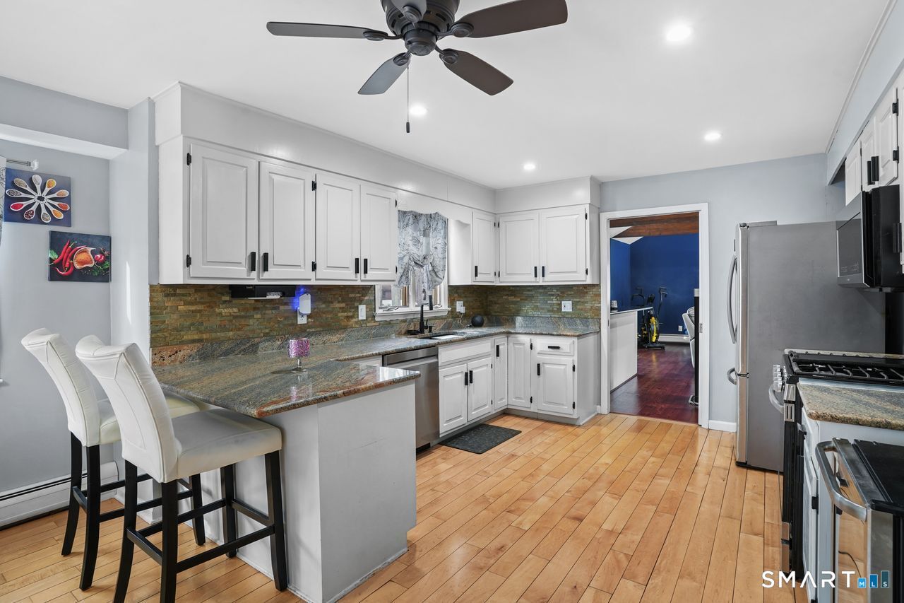 17 Moose Hill Road Trumbull, CT 06611 - Photo 9 of 40 a kitchen with stainless steel appliances granite countertop a stove top oven a sink a refrigerator with white cabinets and wooden floor