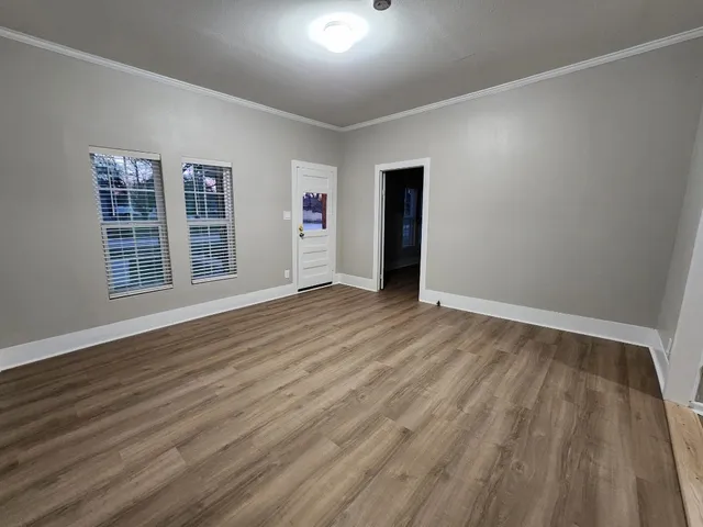 a view of an empty room with wooden floor and windows