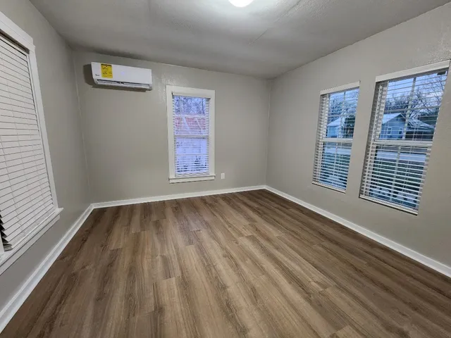 a view of an empty room with a window and wooden floor