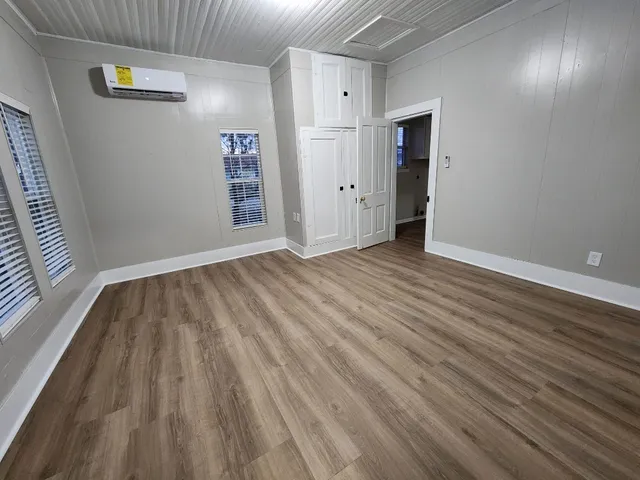 an empty room with wooden floor and windows