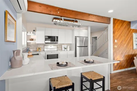 a kitchen with stainless steel appliances kitchen island granite countertop a refrigerator a stove a microwave oven with a dining table and chairs with wooden floor
