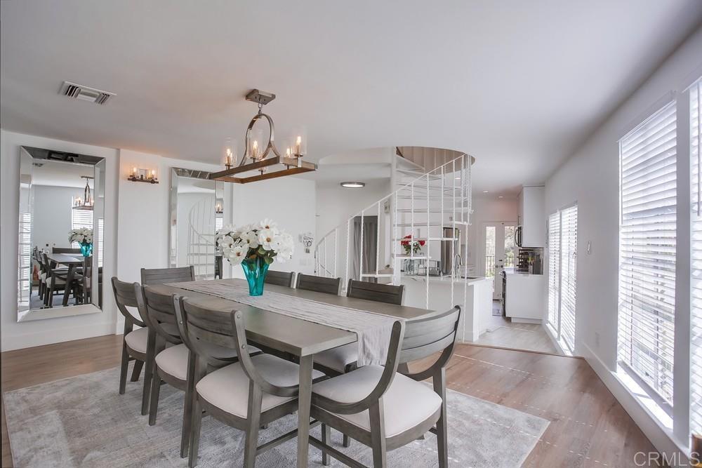 2630 Pirineos Way, Unit 11 Carlsbad, CA 92009 - Photo 5 of 28 a dining room with furniture a chandelier and wooden floor