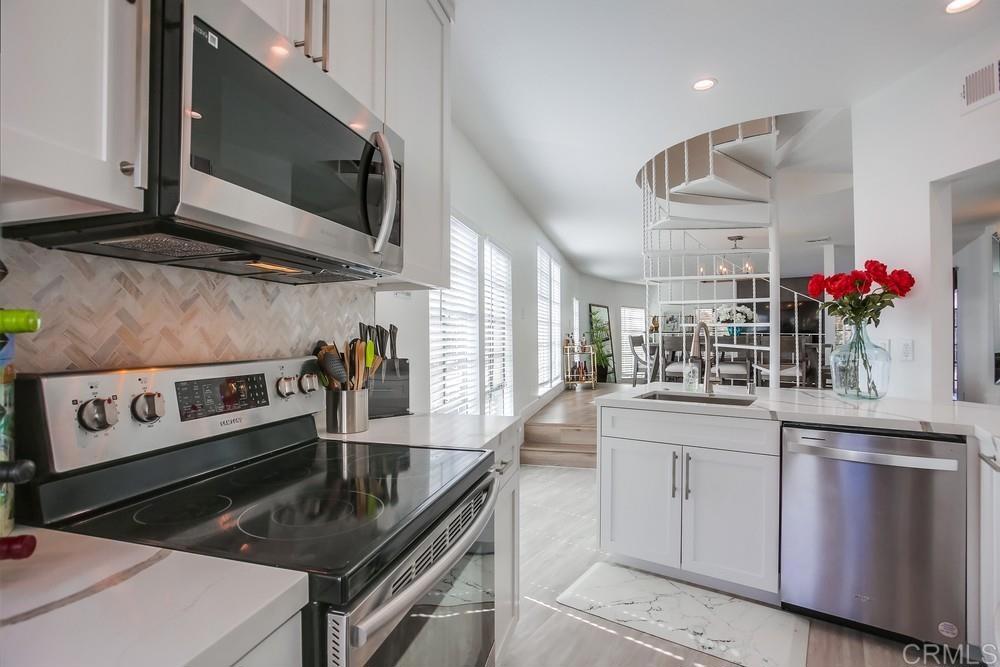 2630 Pirineos Way, Unit 11 Carlsbad, CA 92009 - Photo 8 of 28 a kitchen with stainless steel appliances granite countertop a sink and stove top oven