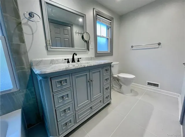 a bathroom with a granite countertop toilet sink and mirror