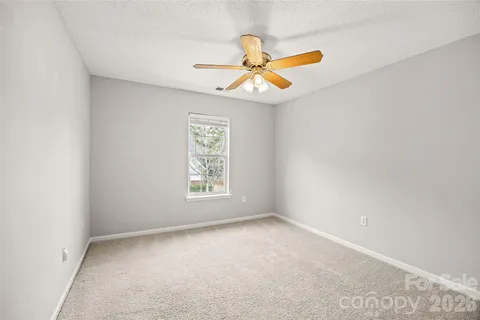 an empty room with a window and a ceiling fan
