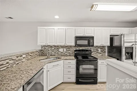 a kitchen with granite countertop white cabinets and stainless steel appliances