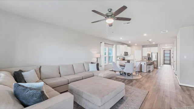a living room with furniture kitchen view and a wooden floor