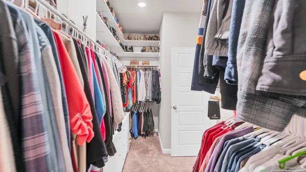 a view of walk in closet with clothes and shoes