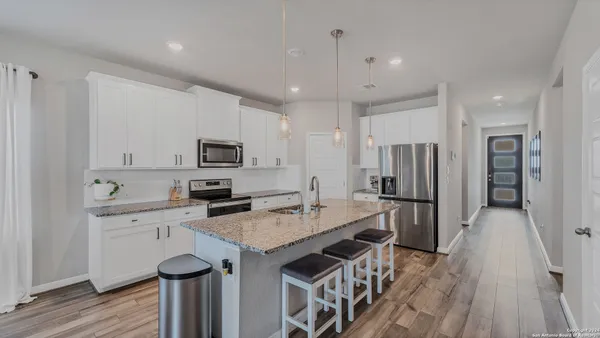 a kitchen with stainless steel appliances granite countertop a refrigerator a stove top oven a sink dishwasher and a refrigerator with wooden floor