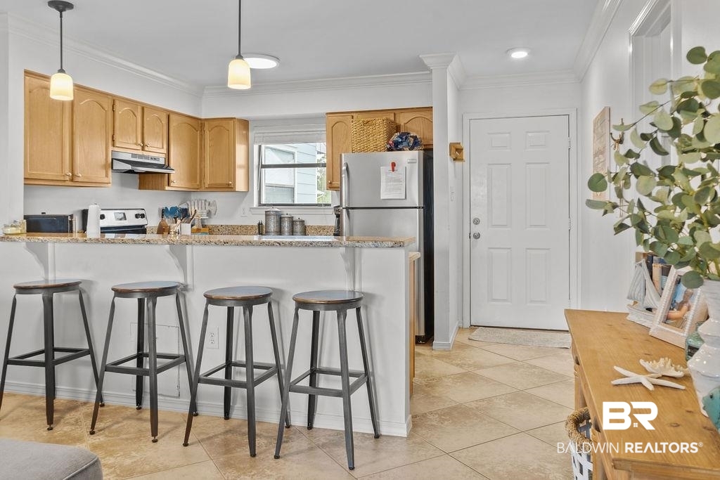 25861 Canal Road, Unit 30 Orange Beach, AL 36561 - Photo 8 of 38 Kitchen featuring light tile patterned flooring, crown molding, a kitchen breakfast bar, and decorative light fixtures