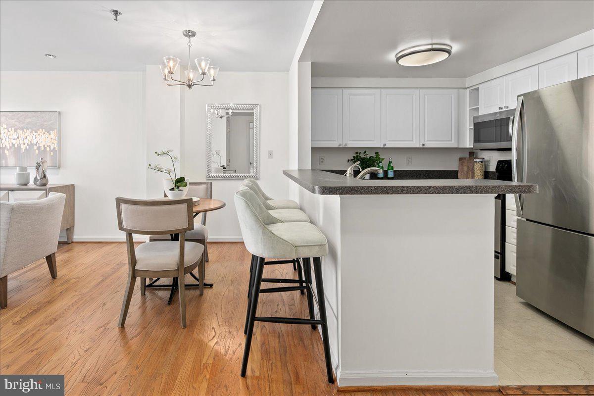 1312 Massachusetts Avenue Northwest, Unit 710 Washington, DC 20005 - Photo 11 of 30 a kitchen with stainless steel appliances a dining table chairs refrigerator and sink