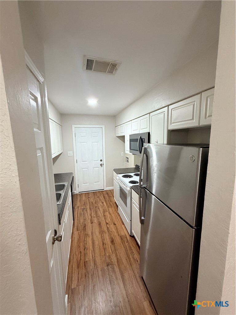 208 Uhland Road, Unit 3 San Marcos, TX 78666 - Photo 3 of 12 a kitchen with a refrigerator a sink and cabinets