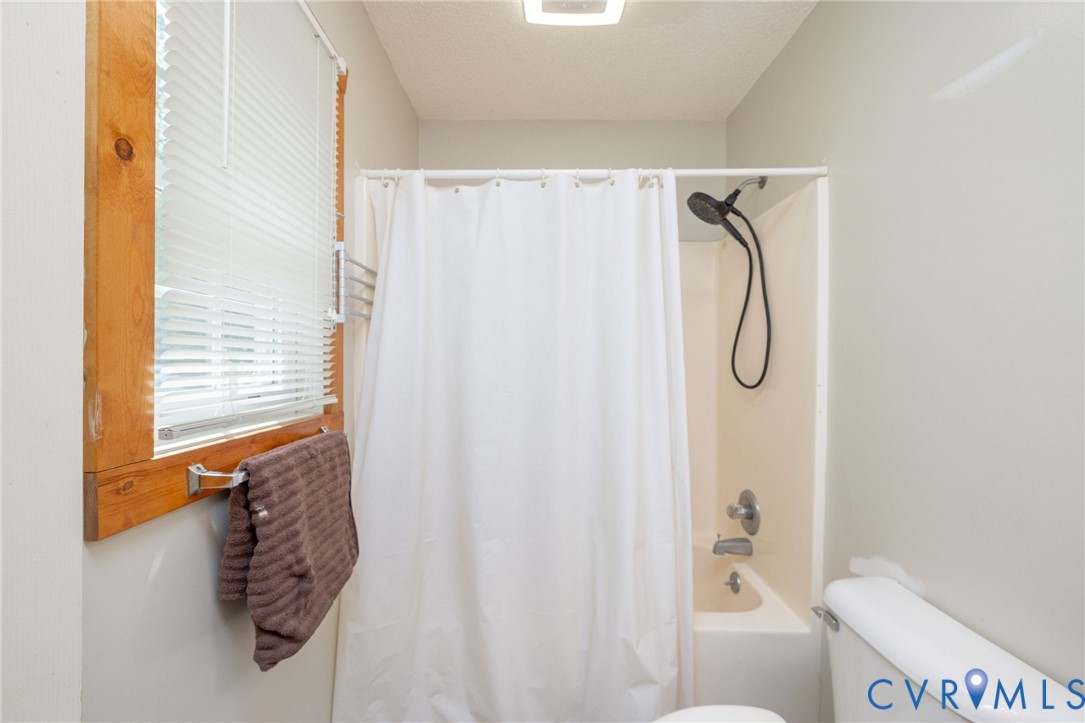 460 Horseshoe Road Jarratt, VA 23867 - Photo 11 of 24 a bathroom with a shower curtain and a window