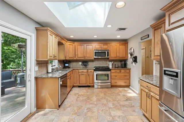 a kitchen with stainless steel appliances granite countertop a refrigerator a stove top oven a sink dishwasher and wooden cabinets