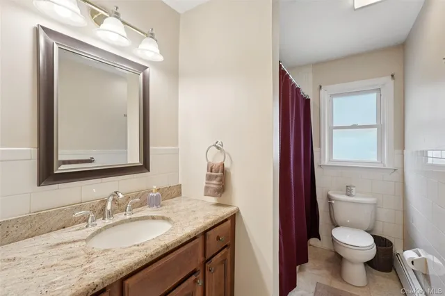 a bathroom with a granite countertop toilet a sink and a mirror