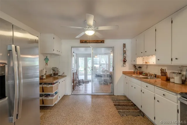 a kitchen with stainless steel appliances a refrigerator a sink a stove and white cabinets