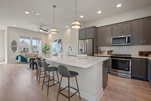 a kitchen with kitchen island a dining table chairs stainless steel appliances and cabinets