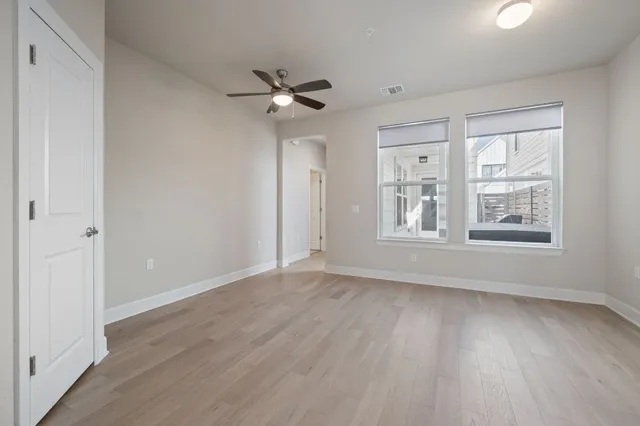 a view of an empty room with a window and wooden floor