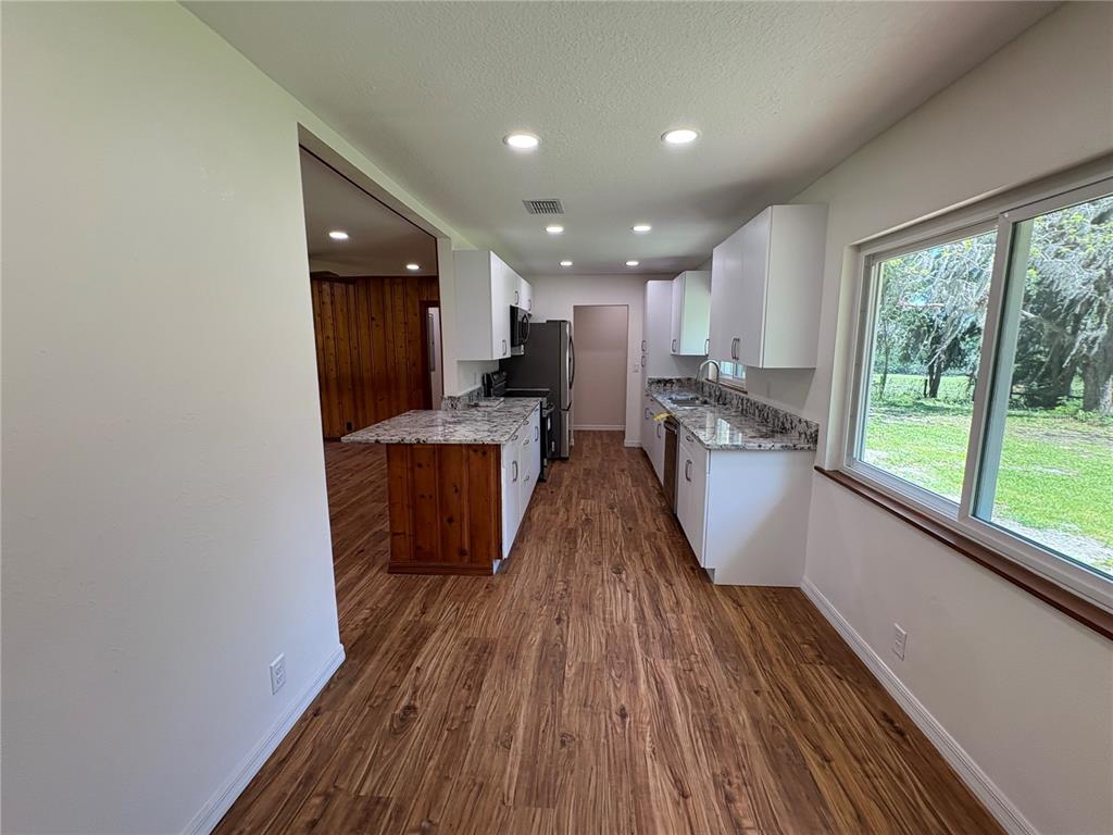 2110 Northwest 100th Street Ocala, FL 34475 - Photo 22 of 44 a view of a kitchen with kitchen island wooden floors and stainless steel appliances