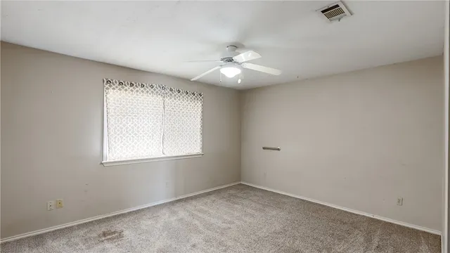 an empty room with windows and ceiling fan