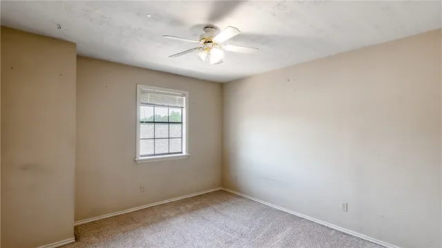 an empty room with windows and chandelier fan