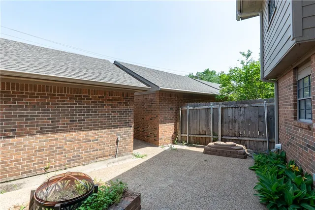 a backyard of a house with barbeque oven and potted plants