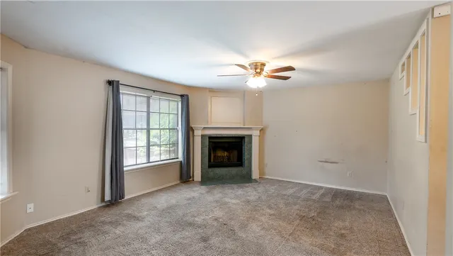 an empty room with chandelier fan and windows