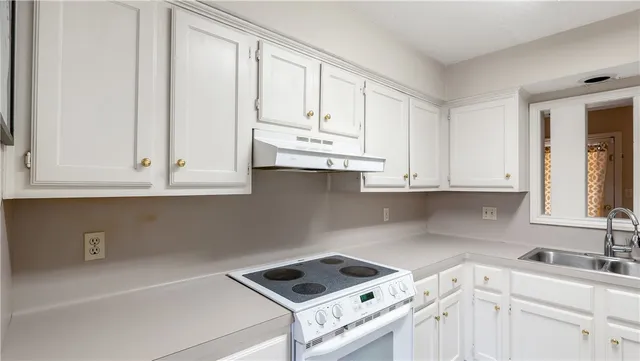 a kitchen with granite countertop white cabinets and white appliances