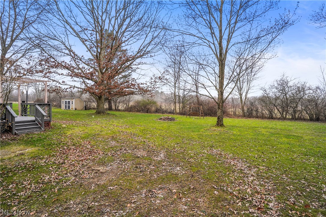 12326 Huntoon Road Painesville, OH 44077 - Photo 10 of 38 View of yard featuring a deck, a fire pit, and an outdoor structure