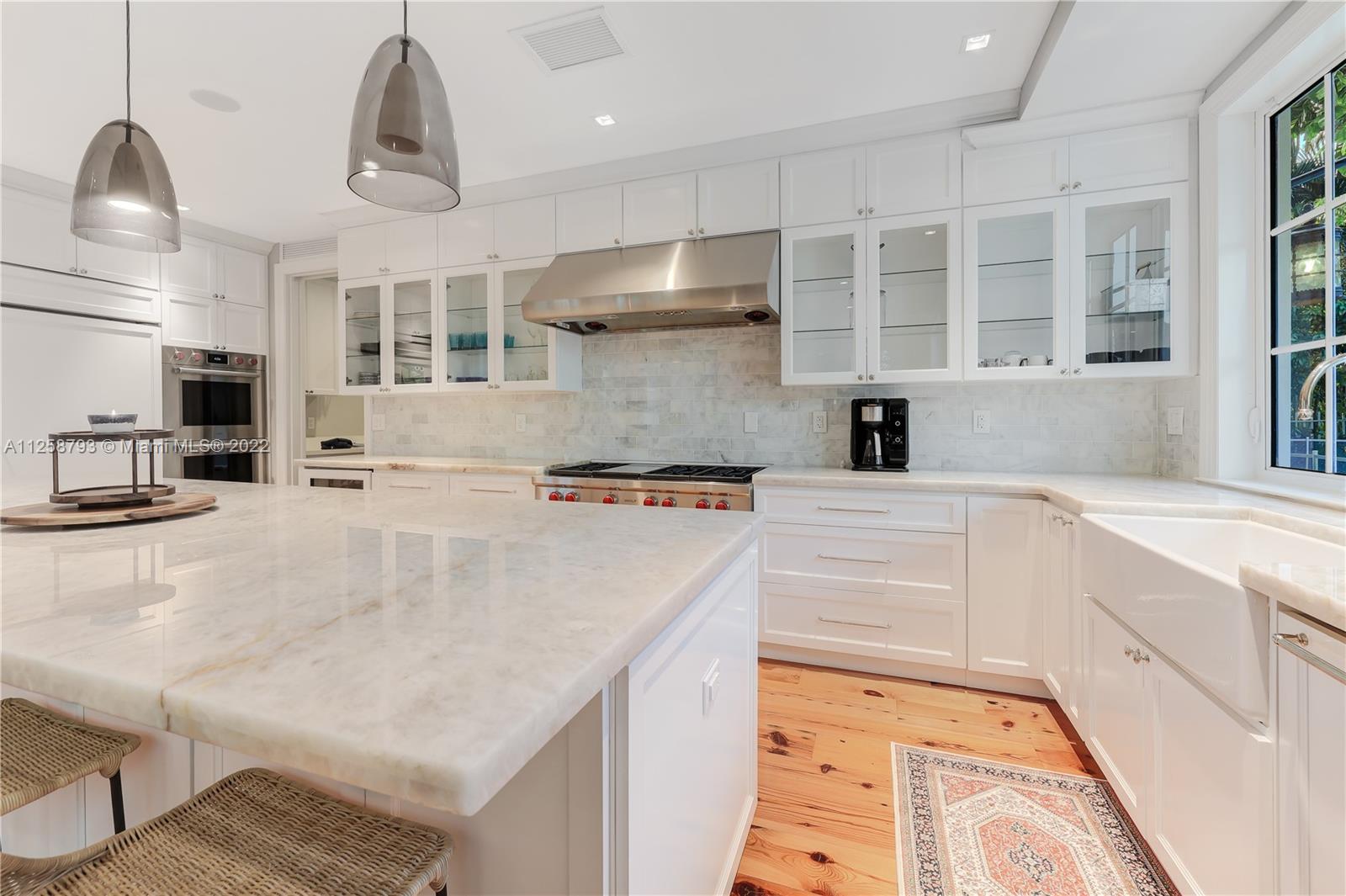 1311 Alhambra Circle Miami, FL 33134 - Photo 17 of 56 a kitchen with a stove a refrigerator and white cabinets with wooden floor