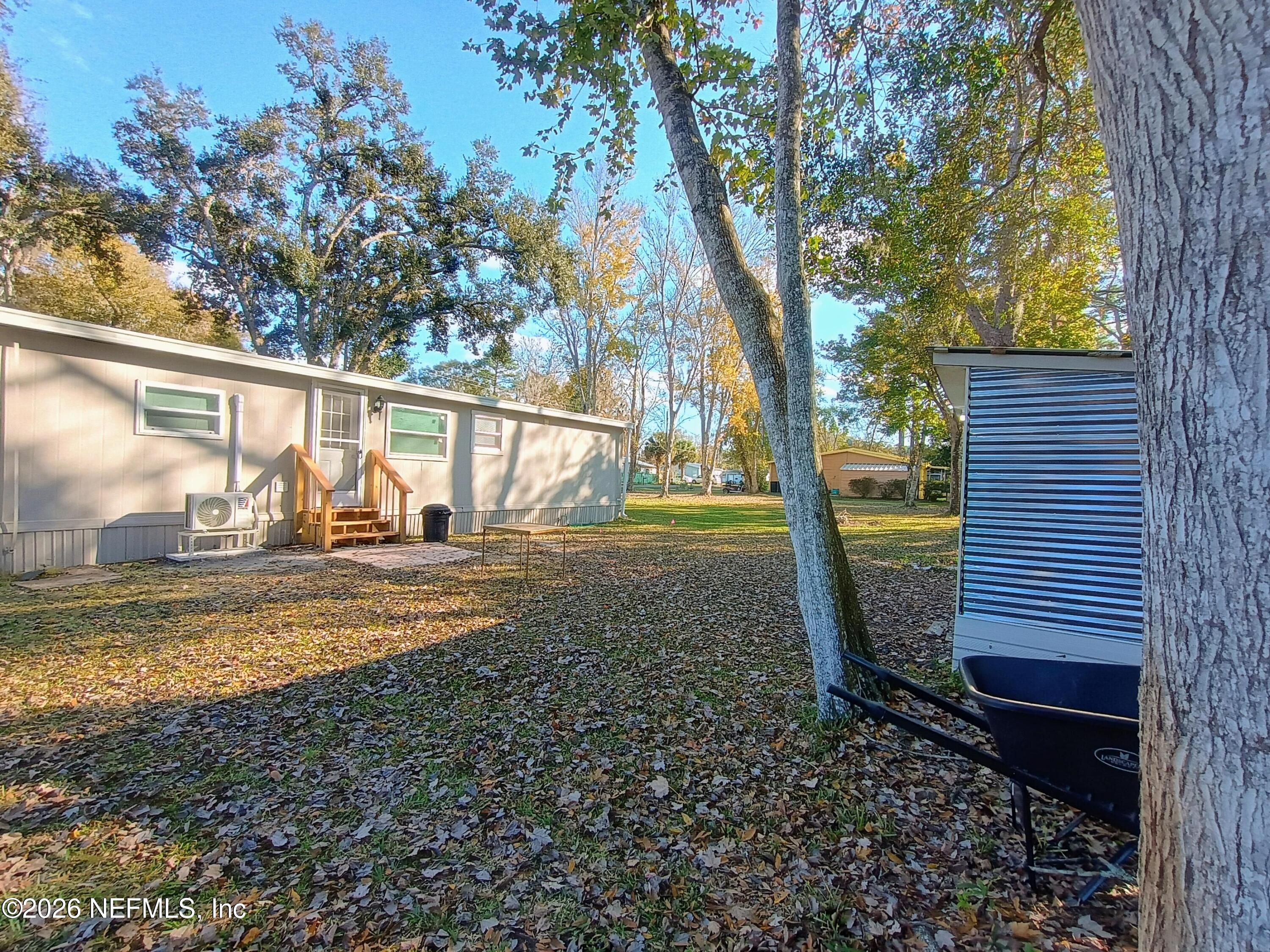 215 Pine Tree Trail Crescent City, FL 32112 - Photo 6 of 25 a view of a backyard with wooden fence and large trees