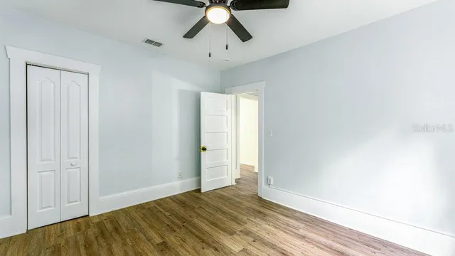 a view of empty room with wooden floor and fan