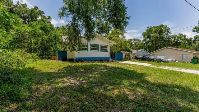 a view of a house with a yard and a large tree