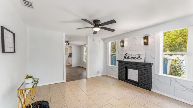 a view of a livingroom with a fireplace a ceiling fan and windows