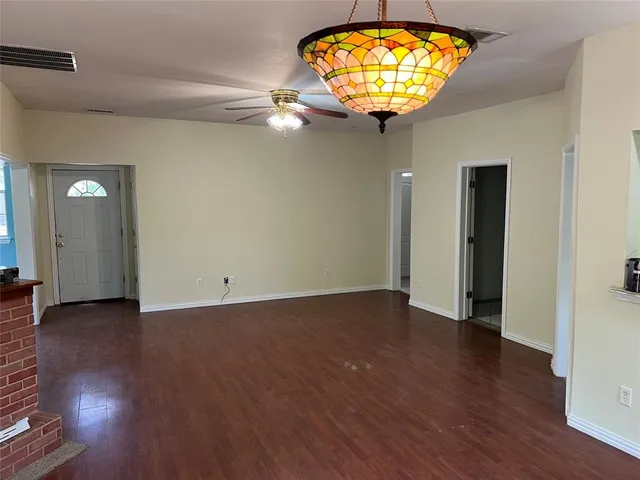an empty room with wooden floor and chandelier