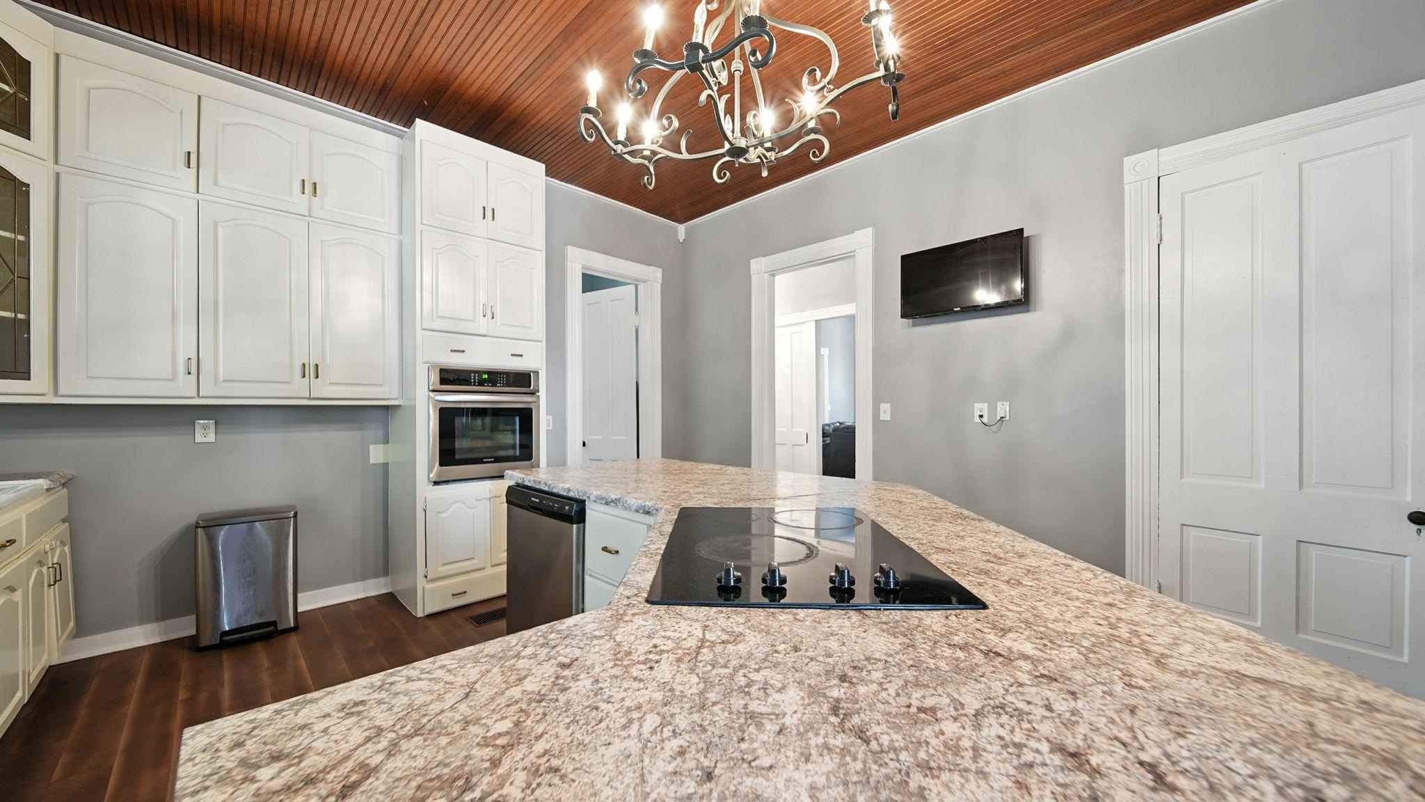 320 North Maple Street Covington, TN 38019 - Photo 14 of 35 Kitchen with appliances with stainless steel finishes, decorative light fixtures, dark wood finished floors, white cabinetry, and wood ceiling