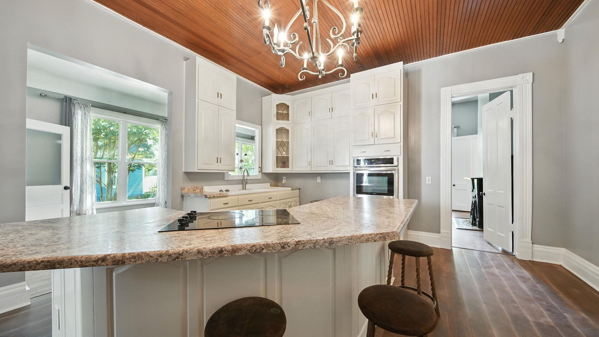 320 North Maple Street Covington, TN 38019 - Photo 15 of 35 Kitchen with a kitchen bar, dark wood finished floors, a kitchen island, white cabinets, and wood ceiling