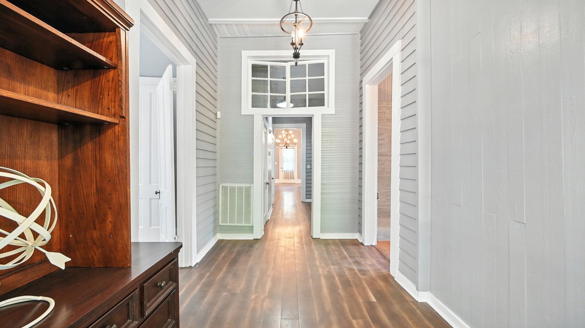 320 North Maple Street Covington, TN 38019 - Photo 24 of 35 Hallway with a chandelier, dark wood-style flooring, and wood walls