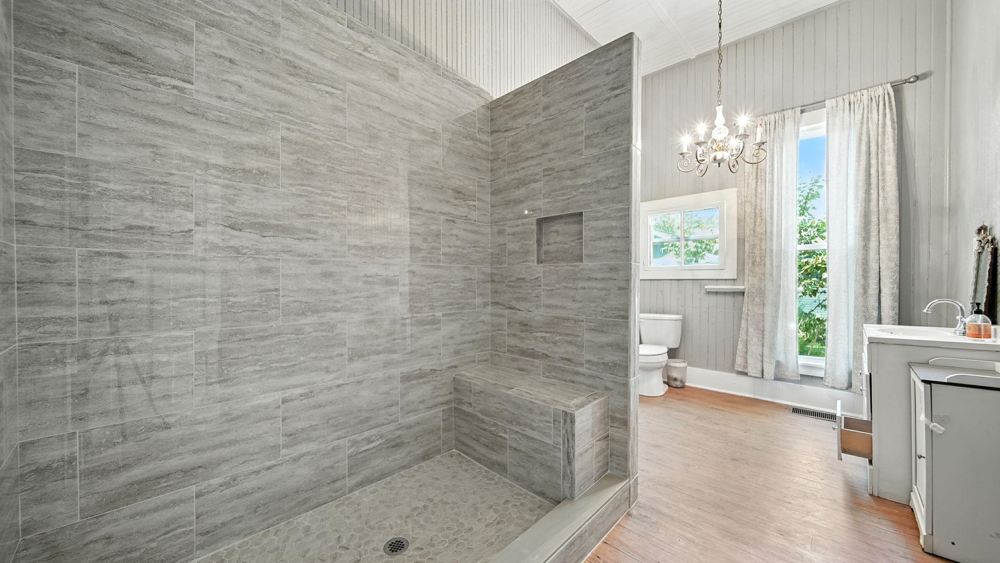 320 North Maple Street Covington, TN 38019 - Photo 29 of 35 Full bath featuring vanity, a tile shower, light wood-style flooring, and a chandelier