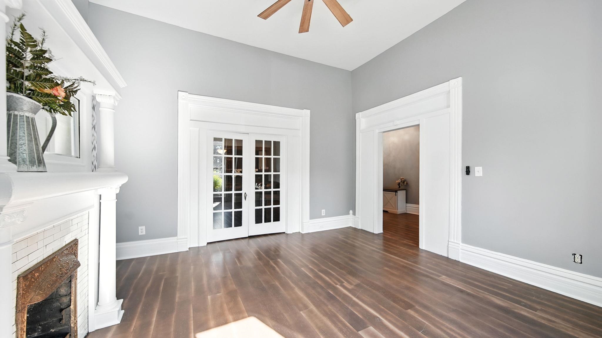 320 North Maple Street Covington, TN 38019 - Photo 34 of 35 Unfurnished living room with french doors, dark wood-style flooring, a fireplace, and ceiling fan