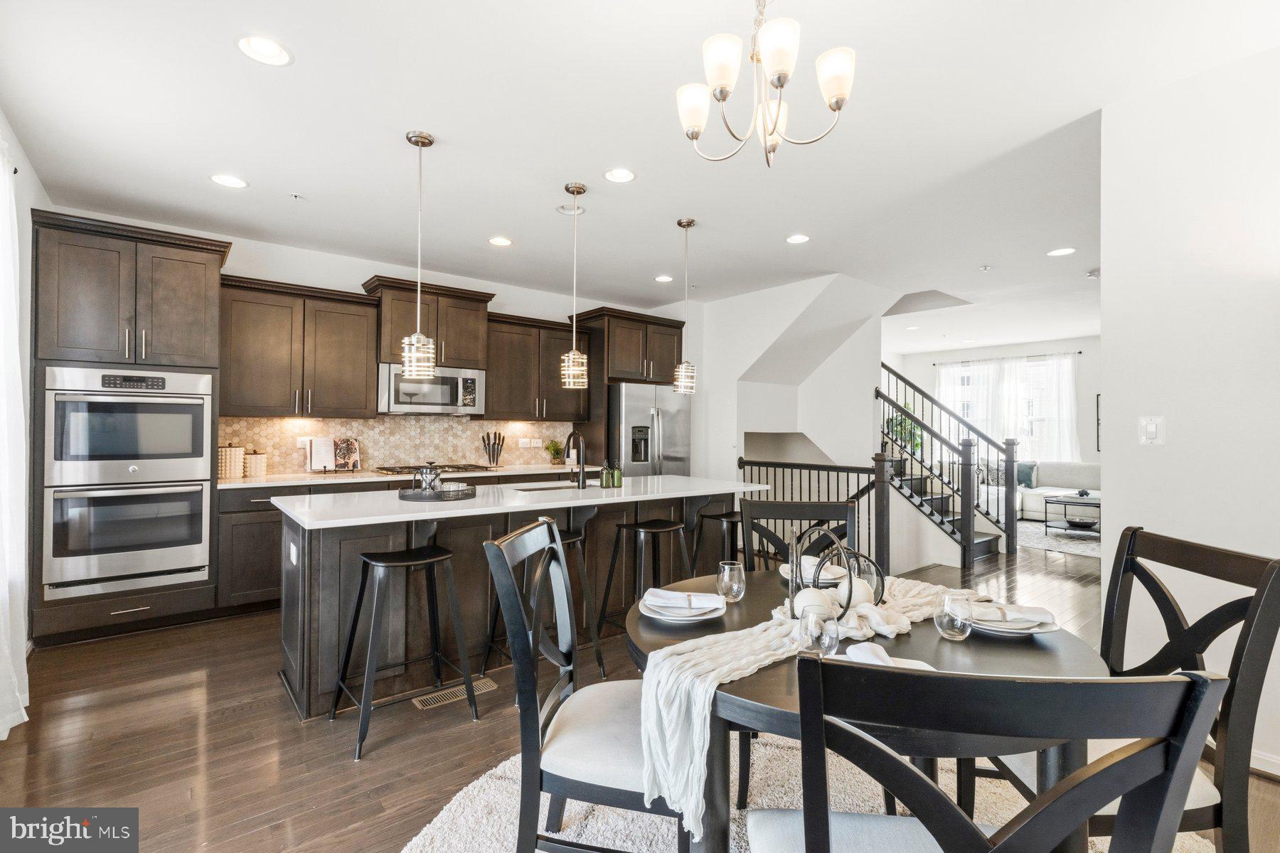 7205 Barry Lane Elkridge, MD 21075 - Photo 3 of 22 a kitchen with stainless steel appliances kitchen island granite countertop a dining table chairs and refrigerator