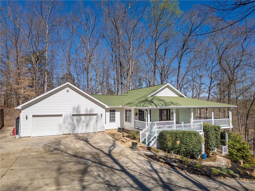 This charming home offers a serene escape with its inviting porch and lush natural surroundings.