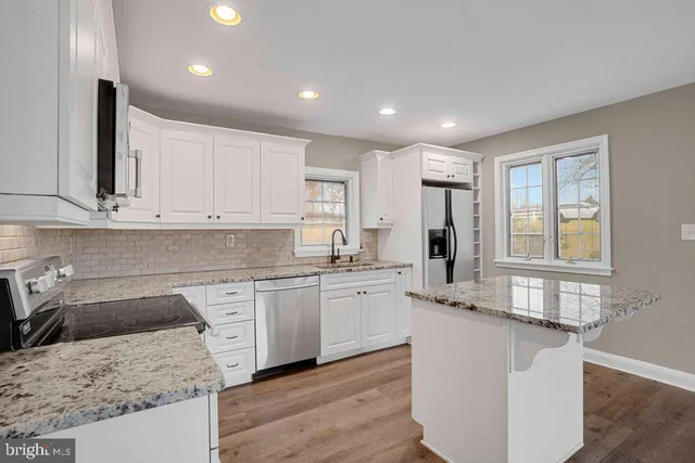 a kitchen that has a lot of white cabinets and wooden floor