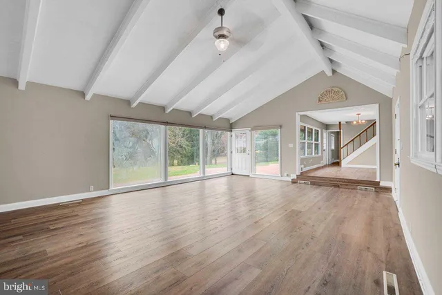an empty room with wooden floor fan and windows