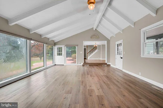a view of empty room with wooden floor and fan