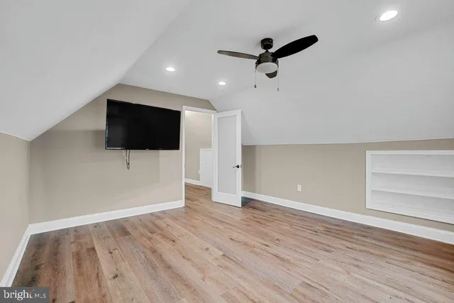 a view of a livingroom with a flat screen tv wooden floor and a ceiling fan